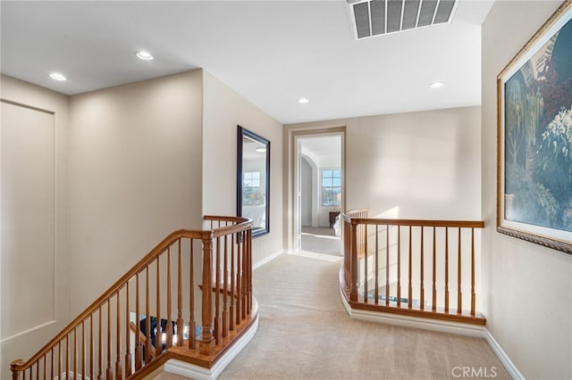 hallway with recessed lighting, visible vents, carpet floors, and an upstairs landing