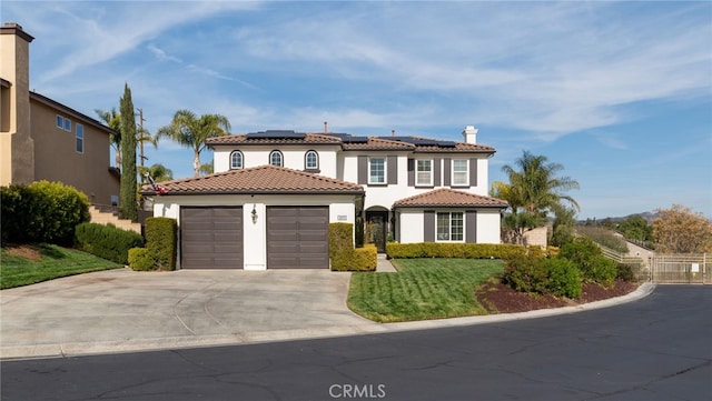 mediterranean / spanish-style house with stucco siding, roof mounted solar panels, fence, a garage, and driveway