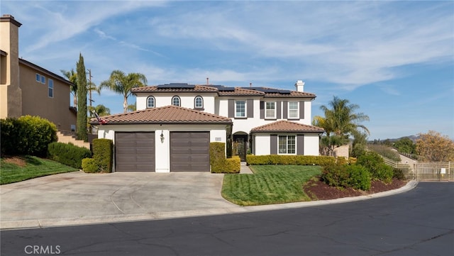 mediterranean / spanish home with roof mounted solar panels, a tiled roof, stucco siding, an attached garage, and concrete driveway