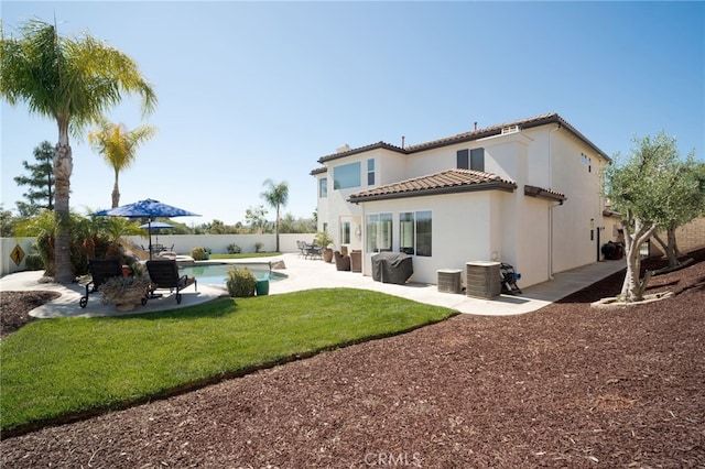 rear view of house with a patio area, a tiled roof, a fenced backyard, a fenced in pool, and stucco siding