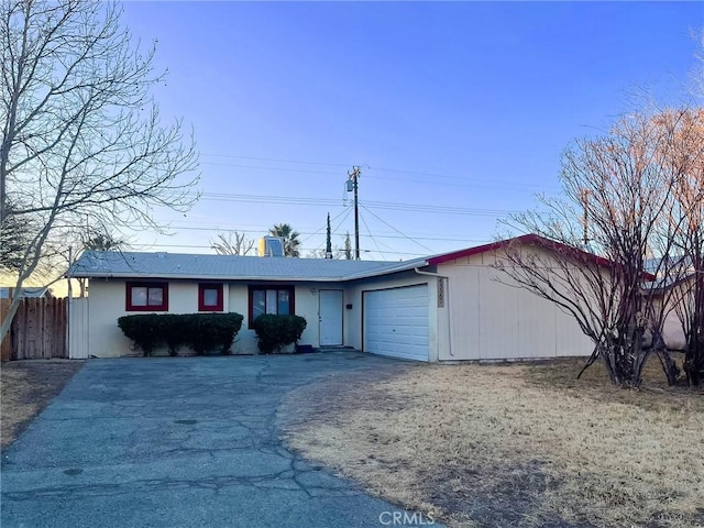 ranch-style house with aphalt driveway, an attached garage, and fence