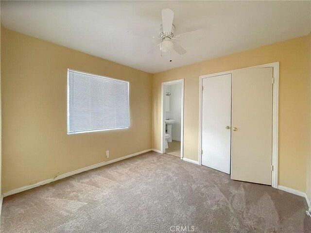 unfurnished bedroom with a ceiling fan, baseboards, connected bathroom, and light colored carpet