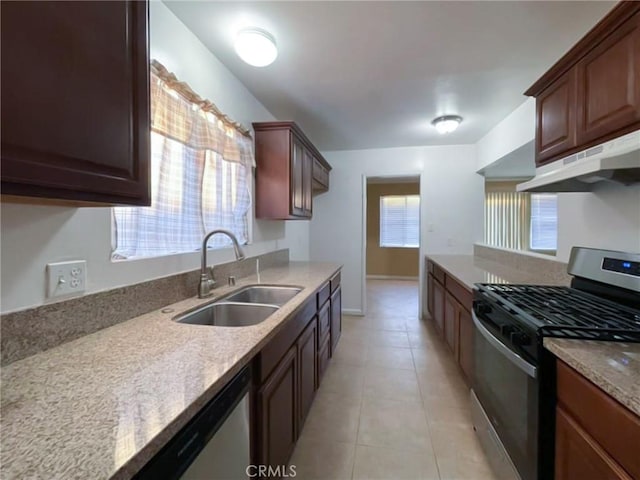 kitchen with light tile patterned floors, stainless steel appliances, a sink, under cabinet range hood, and baseboards