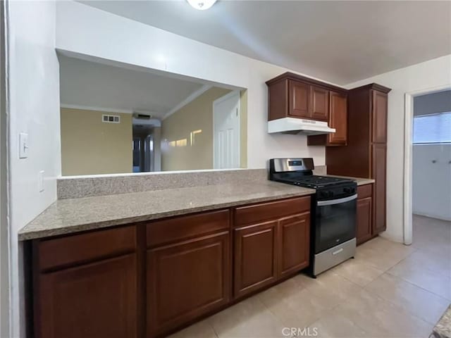 kitchen with stainless steel range with gas cooktop, light tile patterned floors, visible vents, light countertops, and under cabinet range hood