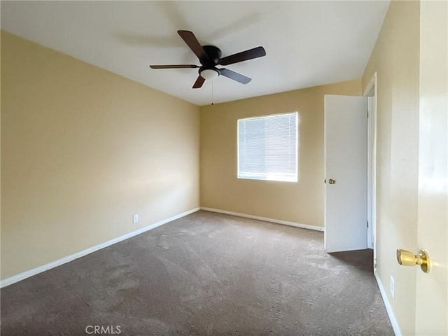 empty room with baseboards, dark colored carpet, and a ceiling fan