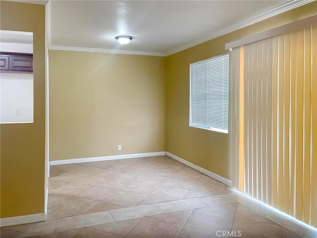 spare room featuring light tile patterned floors, baseboards, and crown molding