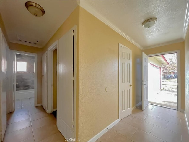 hall with light tile patterned floors, a textured wall, a textured ceiling, baseboards, and crown molding