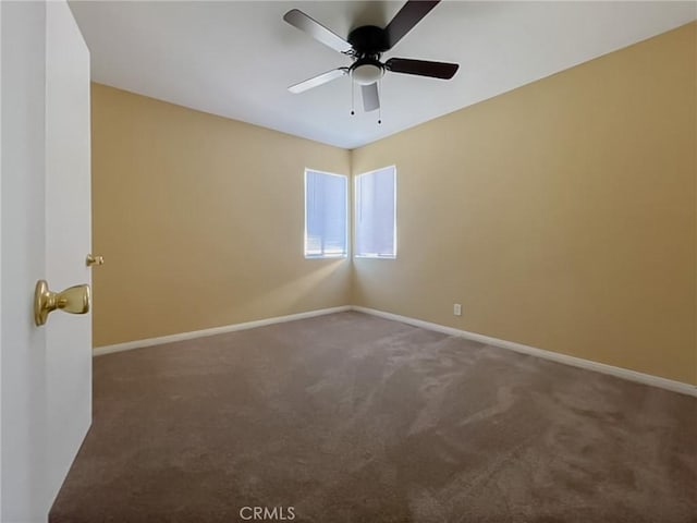 empty room featuring dark carpet, baseboards, and ceiling fan