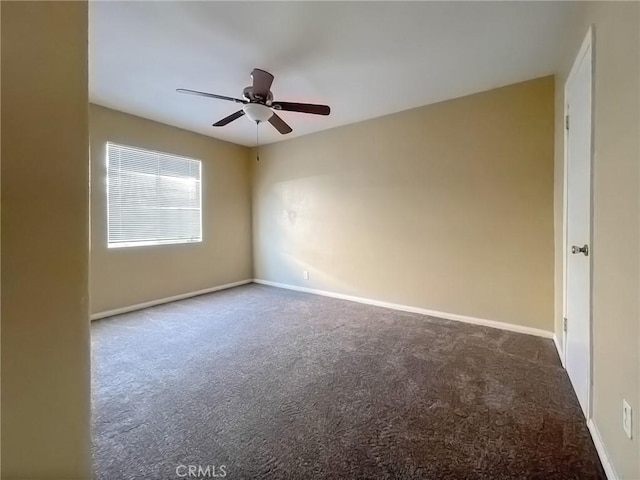 spare room with dark colored carpet, ceiling fan, and baseboards