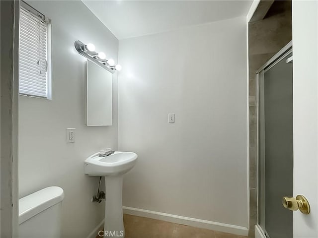 full bathroom with a stall shower, toilet, and baseboards