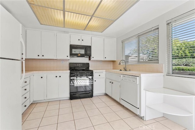 kitchen with light countertops, backsplash, white cabinetry, a sink, and black appliances