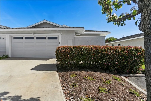 view of side of home featuring an attached garage, driveway, and stucco siding