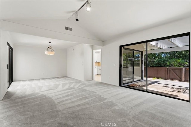 unfurnished room with lofted ceiling, track lighting, visible vents, and light colored carpet