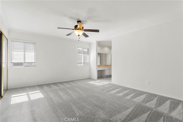 empty room with crown molding, baseboards, a ceiling fan, and light colored carpet