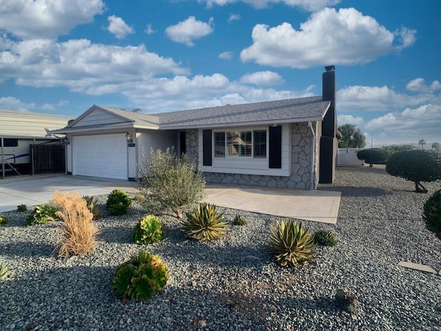 view of front of home with concrete driveway, stone siding, a chimney, and an attached garage