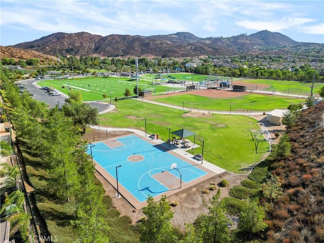 view of sport court with community basketball court, a mountain view, fence, and a yard