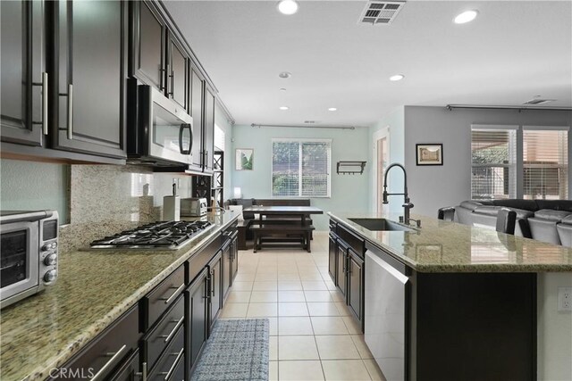 34306 Deergrass Way, Lake Elsinore, CA 92532 - kitchen with light stone countertops, appliances with stainless steel finishes, a sink, an island with sink, and visible vents