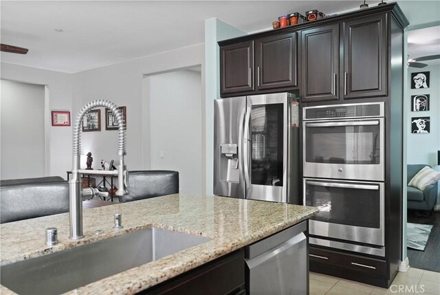 34306 Deergrass Way, Lake Elsinore, CA 92532 - kitchen with appliances with stainless steel finishes, dark brown cabinets, a sink, light tile patterned floors, and light stone counters