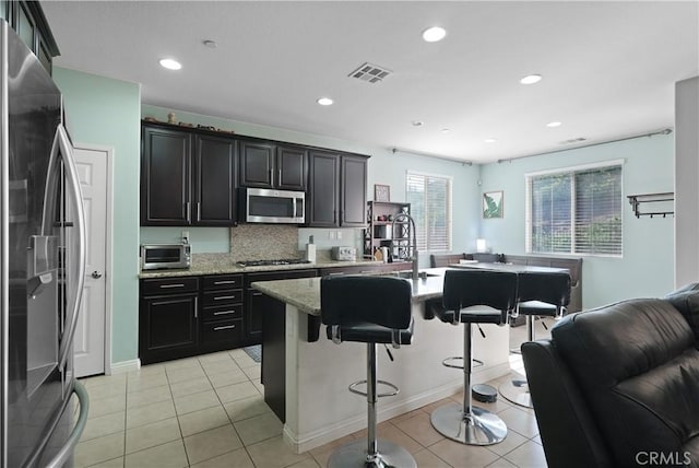 kitchen featuring stainless steel appliances, visible vents, a kitchen breakfast bar, and light tile patterned floors