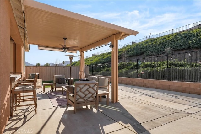 view of patio featuring ceiling fan, fence, and an outdoor living space