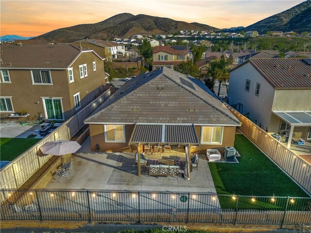 34306 Deergrass Way, Lake Elsinore, CA 92532 - back of house at dusk with a patio, a residential view, a mountain view, and a fenced backyard