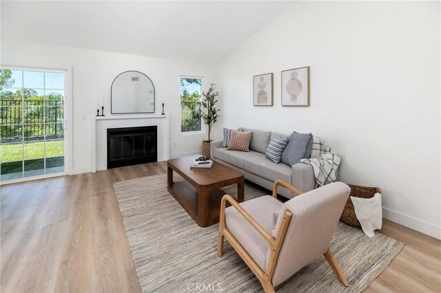 7969 Calle Madrid, Carlsbad, CA 92009 - living room with plenty of natural light, light wood-type flooring, vaulted ceiling, a glass covered fireplace, and baseboards