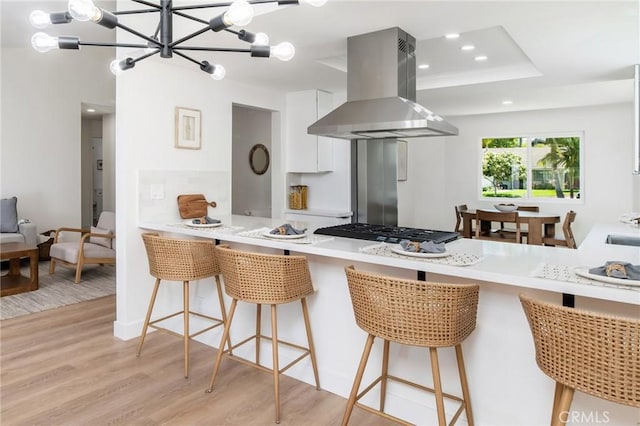 7969 Calle Madrid, Carlsbad, CA 92009 - kitchen featuring island range hood, gas cooktop, light wood-style flooring, white cabinetry, and a peninsula