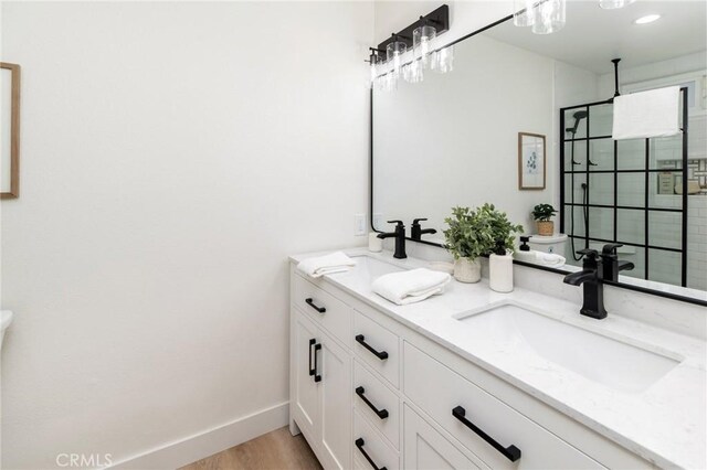 7969 Calle Madrid, Carlsbad, CA 92009 - bathroom featuring toilet, double vanity, tiled shower, wood finished floors, and baseboards