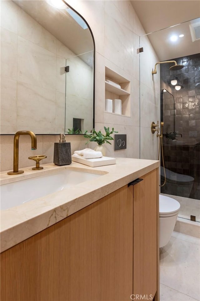 bathroom with toilet, a shower stall, tile walls, and vanity