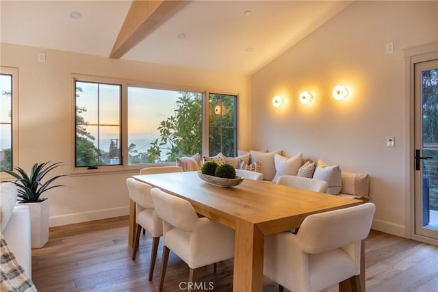 dining space featuring light wood-style floors, baseboards, and vaulted ceiling