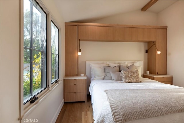 bedroom featuring lofted ceiling with beams and wood finished floors