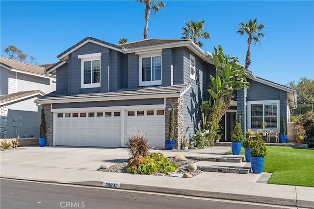 traditional home featuring a garage, stone siding, a front lawn, and concrete driveway