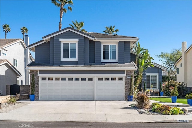 traditional-style home featuring a garage, stone siding, and driveway