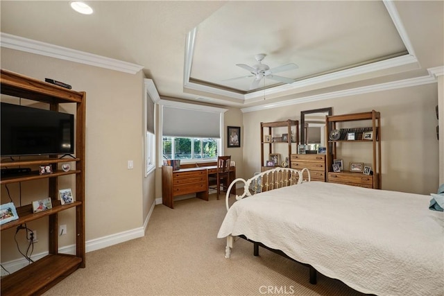 bedroom featuring light colored carpet, a ceiling fan, baseboards, ornamental molding, and a tray ceiling