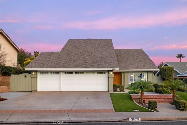 view of front facade with a garage, concrete driveway, roof with shingles, and stucco siding