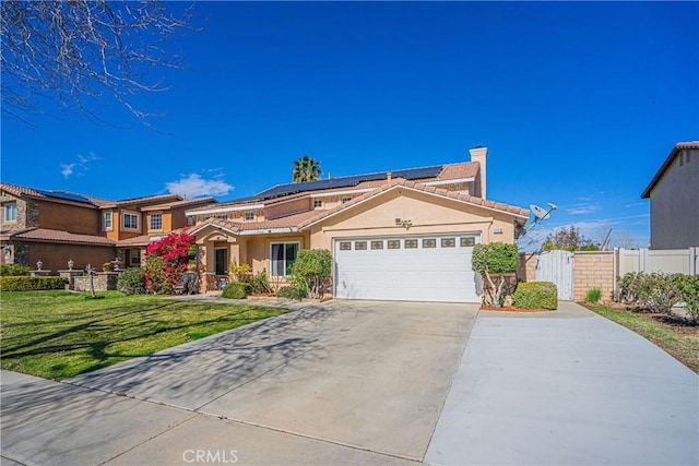 view of front of home featuring an attached garage, solar panels, fence, driveway, and a front yard