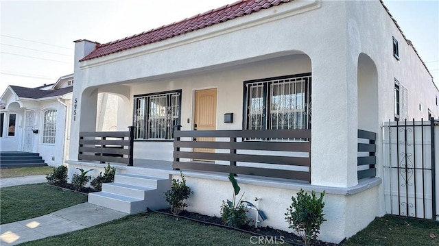 exterior space with a porch, a tile roof, and stucco siding