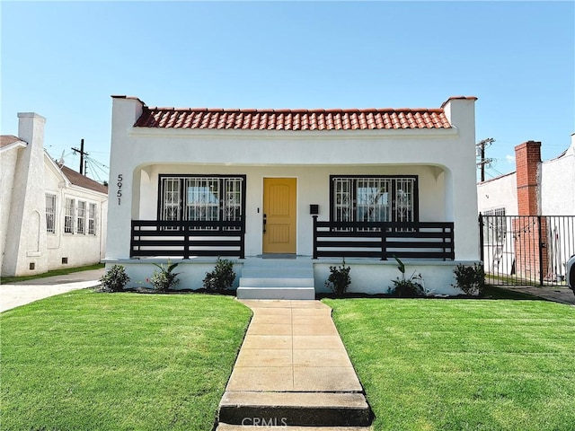 mediterranean / spanish-style home featuring stucco siding, covered porch, a front lawn, and a tile roof