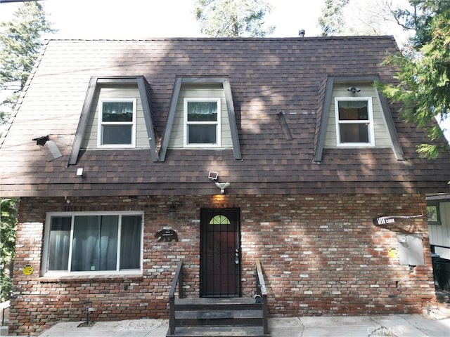 view of front of property featuring a shingled roof, entry steps, and brick siding