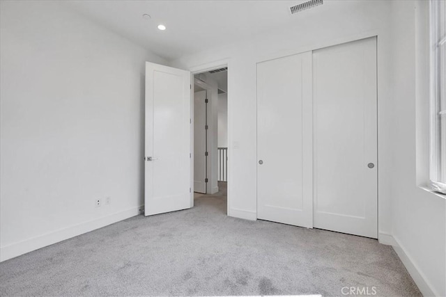 unfurnished bedroom featuring recessed lighting, light colored carpet, visible vents, baseboards, and a closet