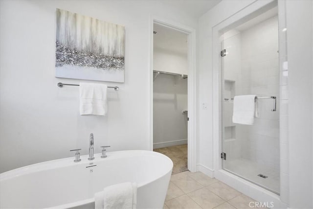 full bath featuring a freestanding tub, a spacious closet, a shower stall, and tile patterned floors