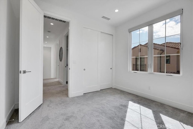 unfurnished bedroom featuring light carpet, visible vents, a closet, and recessed lighting