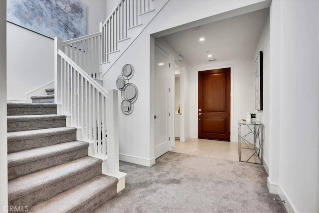 foyer featuring light tile patterned floors, recessed lighting, light carpet, baseboards, and stairs