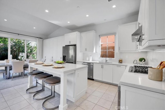 kitchen featuring stainless steel appliances, light countertops, white cabinets, a kitchen island, and a kitchen bar