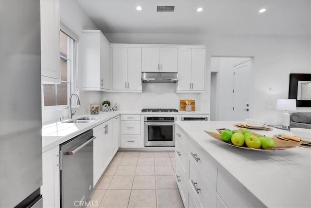 kitchen with under cabinet range hood, stainless steel appliances, visible vents, white cabinets, and light countertops