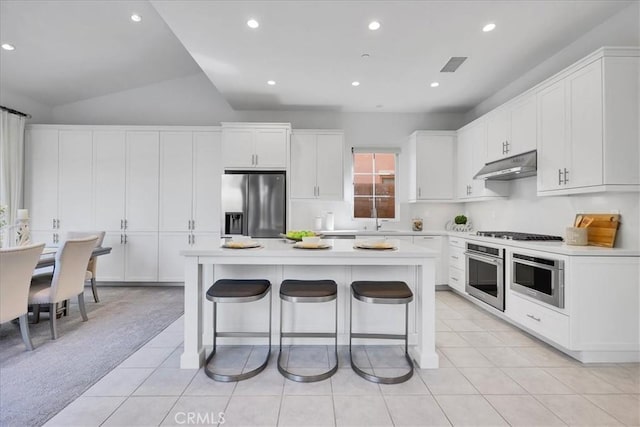 kitchen featuring stainless steel appliances, light countertops, a kitchen island, and under cabinet range hood