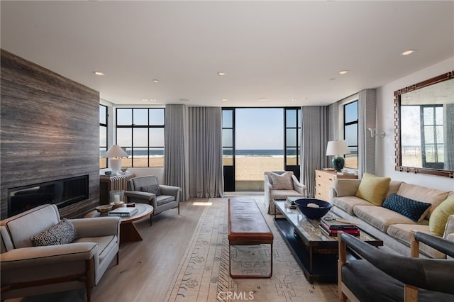 living area featuring a water view, recessed lighting, light wood finished floors, and a large fireplace