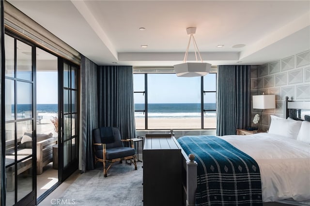 bedroom with a water view, multiple windows, and a view of the beach