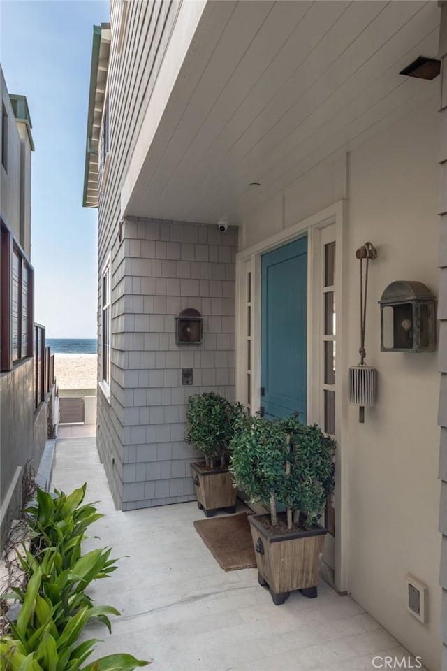 view of exterior entry featuring a patio area and a water view