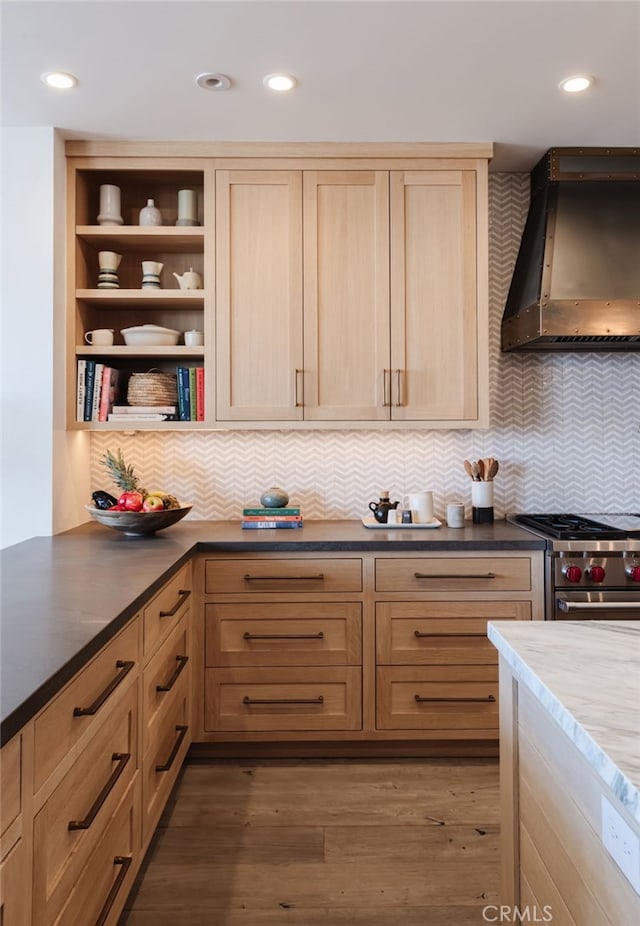 kitchen featuring high end range, backsplash, open shelves, wall chimney exhaust hood, and light brown cabinetry